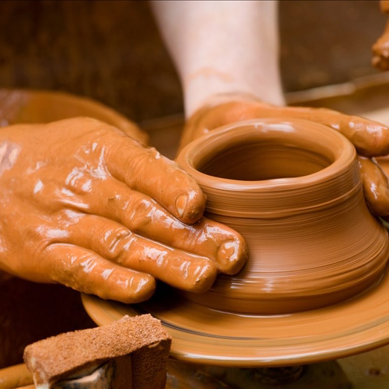 Potter shaping a ceramic plate on a pottery wheel